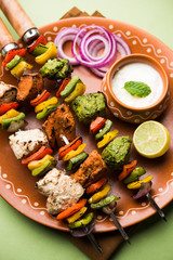 Chicken Hariyali kakab or Malai malai kebab served with skewers and yogurt dip in a plate. selective focus