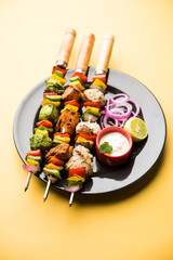 Chicken Hariyali kakab or Malai malai kebab served with skewers and yogurt dip in a plate. selective focus