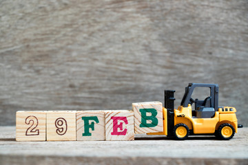 Toy forklift hold block B to complete word 29feb on wood background (Concept for calendar date 29 in month February, leap day)