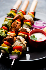 Chicken Hariyali kakab or Malai malai kebab served with skewers and yogurt dip in a plate. selective focus