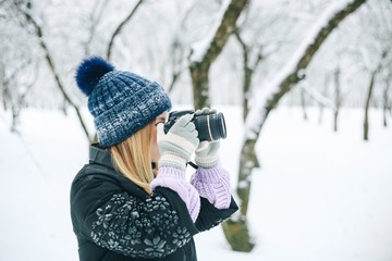 young girl photographer in the winter snowy park photographs nature.