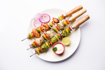 Chicken Hariyali kakab or Malai malai kebab served with skewers and yogurt dip in a plate. selective focus