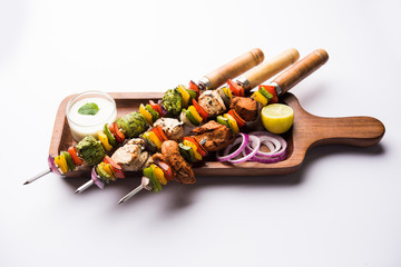 Chicken Hariyali kakab or Malai malai kebab served with skewers and yogurt dip in a plate....