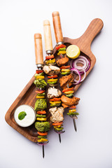 Chicken Hariyali kakab or Malai malai kebab served with skewers and yogurt dip in a plate. selective focus
