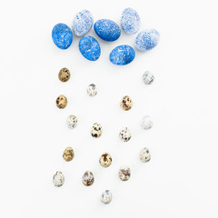 Blue Easter eggs with quail eggs on white background. Flat lay. Top view. Cloud and rain made of easter eggs, creative concept