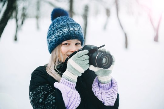 young girl photographer in the winter snowy park photographs nature.