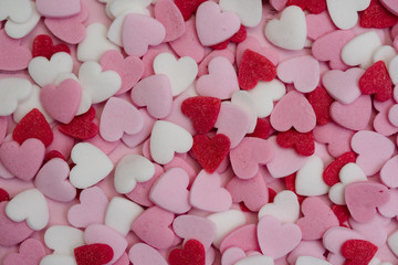 Close up flatlay shot of hundreds of small heart-shaped sugar sprinkles in red, pink and white for Valentine's day card, symbol for love, emotion or romantic feelings as background or wallpaper image