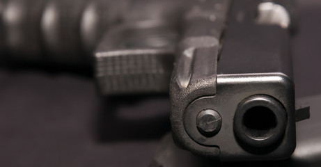 A black 9mm semiautomatic pistol laying in it's side on a black background