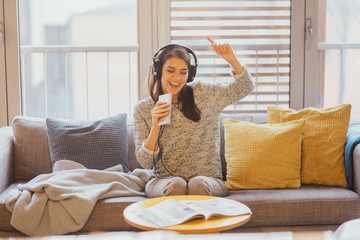 Singing song with emotion.Practicing vocal abilities. Improving range.Cheerful woman listening to music with large headphones and singing.Relaxing with music,happy woman singing.Positive mood - obrazy, fototapety, plakaty
