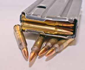 Fototapeta premium A loaded AR-15 rifle magazine on top of four .223 caliber bullets on a white background