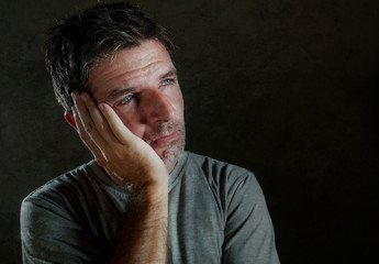 isolated dark background portrait of 30s to 40s sad and depressed man looking thoughtful and worried suffering depression problem with dramatic face expression