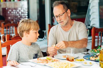 Family in the restaurant, father and sun eating shrimps, summer vacation by the sea