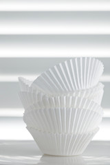 Stack of Empty Cupcake Cases over White Slat Background