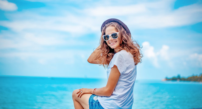 summer portrait of young sexy pretty woman, wearing simple casual trendy white t-shirt and shorts  and bright sunglasses, smiling having fun on vacation in tropical country
