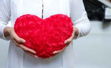 Closeup of red heart-shape handmade souvenir show by woman's hands. The symbol of love forever, valentine day. 
