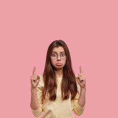 Dejected dissatisfied woman has sorrowful expression, frowns from dislike, has pleasant appearance,...