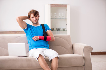 Fototapeta na wymiar Young man with injured arm sitting on the sofa 