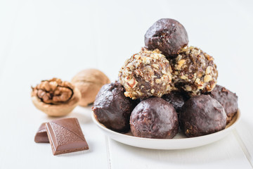Walnut, pieces of chocolate and balls of nuts, dried fruits and chocolate on the black table.
