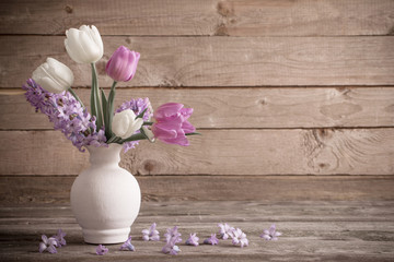 spring flowers in vase on old wooden background