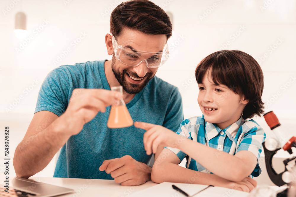 Wall mural Youn Bearded Father Teaching Son in Shirt at Home.