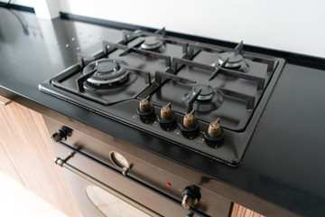 Modern gas burner and hob on a kitchen range. Dark black color and wooden Small kitchen in a modern...