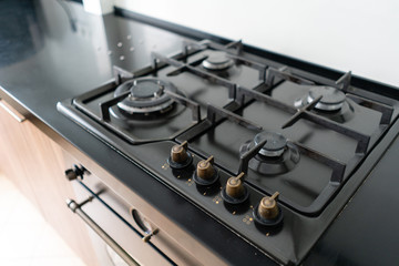 Modern gas burner and hob on a kitchen range. Dark black color and wooden Small kitchen in a modern apartment