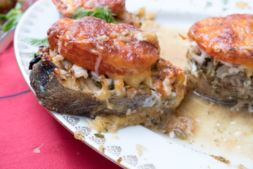 A piece of cod fish baked with tomatoes and cheese on a plate