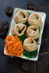 Plate with steamed asian dumplings, seaweed and carrot salad, studio shot, selective focus