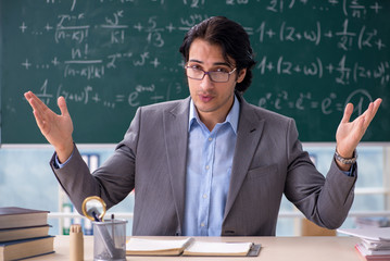 Young handsome math teacher in classroom 