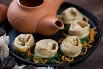 Close-up of steamed dumplings with salmon stuffing, salad and tea, horizontal shot, selective focus