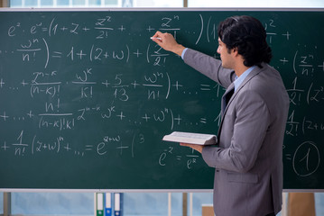 Young handsome math teacher in classroom 