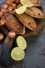 Roasted fish cutlets with cherry tomatoes, lemon and lime. Studio shot, close-up