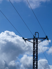 Poste de tendido eléctrico sobre un cielo azul con nubes