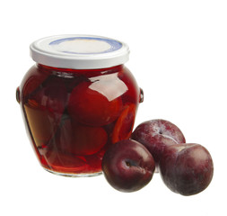 Fresh plums and plum compote in a glass jar.
