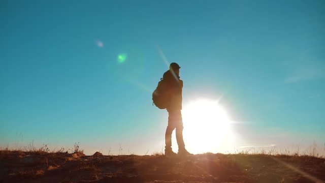 Male man worth it tourist with backpack smartphone navigation sunlight stands on top of a mountain. slow motion video. man silhouette at sunset. lifestyle hikers adventure and the go walking. travel