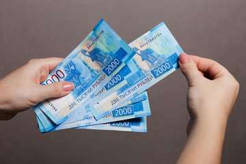Woman holding stack of two thousand Russian Rubles banknotes. 