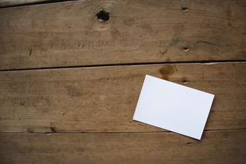 top view of white postcard or paper on old wooden background