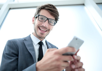 businessman looking at the camera and holding the phone in his h