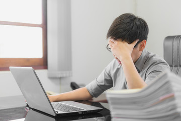Businessman having stress with laptop computer working in the office,Exhausted asian man touching his head, he is having a bad headache, stress and overwork concept.