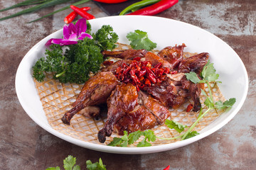 Roast pigeon with dry red pepper in a white dish
