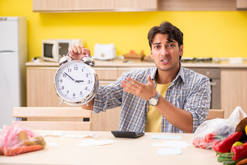Young man calculating expences for vegetables in kitchen 