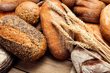 heap of assorted loafs of bread on wooden background