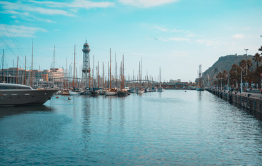 Port of Barcelona, Spain. Yachts, sailing boats and old big tower. Teal and orange view