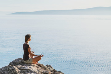 Young woman practicing yoga outdoors. Healthy lifestyle, harmony, meditation  and travel concept