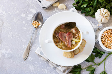 Thick pea soup with smoked meats in a white plate