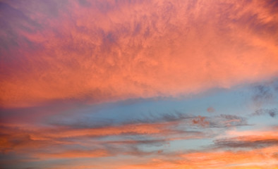 Naklejka na ściany i meble Orange and pink clouds during sunset on blue sky, background