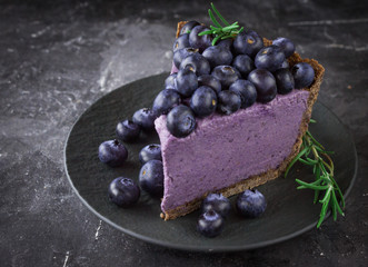 Blueberry vegan cheesecake. Dark photo on black background