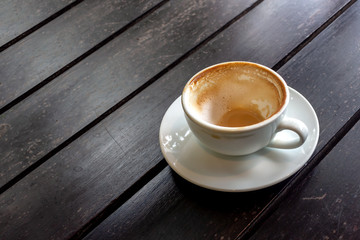 hot coffee that has almost been drunk on black wood background