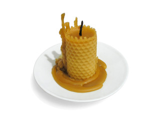 Extinguished beeswax candle on a white saucer isolated on white background