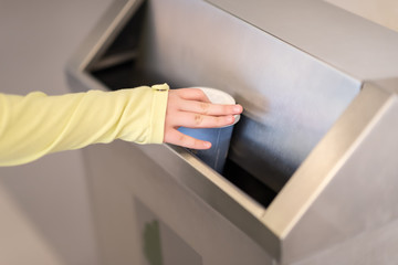 Closeup hand throwing empty paper disposable coffee cup in recycling bin. Recycling, eco friendly...